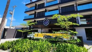 Un immeuble à plusieurs étages doté de balcons, d’un palmier et d’une enseigne indiquant « VEM VEM ».
