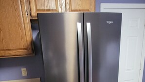 A stainless steel refrigerator in a kitchen with wooden cabinets and a tiled floor. - Stylish 3 BR home in Downtown Lexington (Lexington)