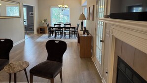 A spacious living room with a fireplace, dining area, and a large window. - Stylish 3 BR home in Downtown Lexington (Lexington)