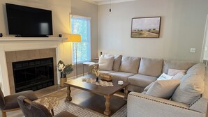A living room with a fireplace, sofa, coffee table, and TV. - Stylish 3 BR home in Downtown Lexington (Lexington)
