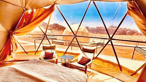 Eine Zelthütte mit Bett, Stühlen und Blick auf die Landschaft.