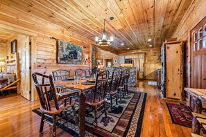 A wooden interior with a dining area, wooden ceiling, and a large painting on the wall. - Valley Views | Hot Tub, Sauna, Game Room | Sleeps 14 (Sevierville)
