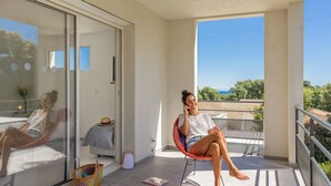 Un balcon offrant une vue dégagée sur la mer, une chaise, une petite table et un panier.