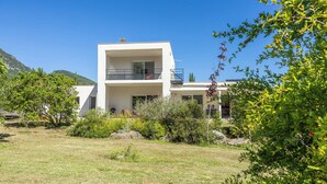 Un bâtiment moderne à deux étages, doté d’un balcon, entouré de verdure et surplombant un ciel dégagé.