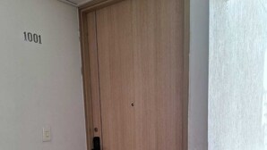 A wooden door with a doorknob, a "WELCOME" mat, and a number "1001" on the wall.