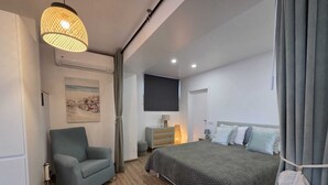 A modern bedroom with a bed, a chair, a desk, and a wall-mounted TV. - Cosy Apartment in Espiche near Praia da Luz (Luz)
