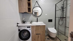 A compact bathroom with a washing machine, a sink, and a toilet. - Cosy Apartment in Espiche near Praia da Luz (Luz)
