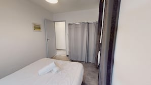 Een hotelkamer met een bed, een deur en een gordijn.
