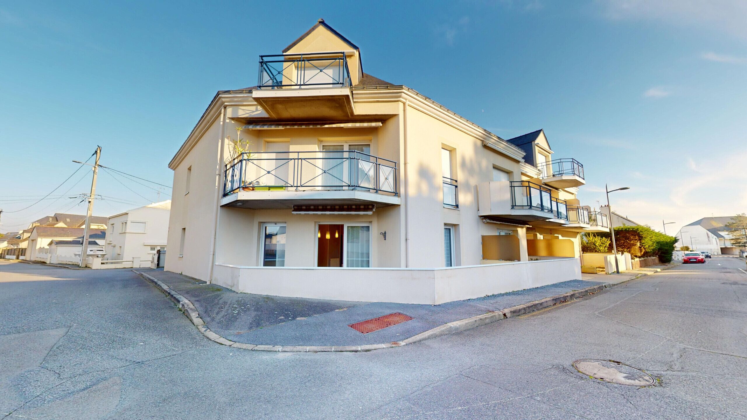 Een woonhuis met twee verdiepingen, een balkon op de bovenverdieping, een garage en een kleine voortuin.