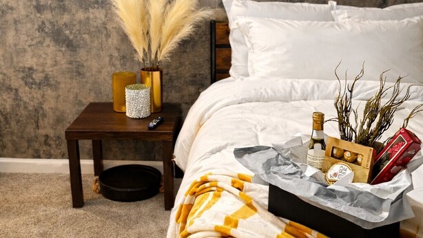 Un dormitorio con cama, mesita de noche, espejo y bandeja con artículos de aseo.