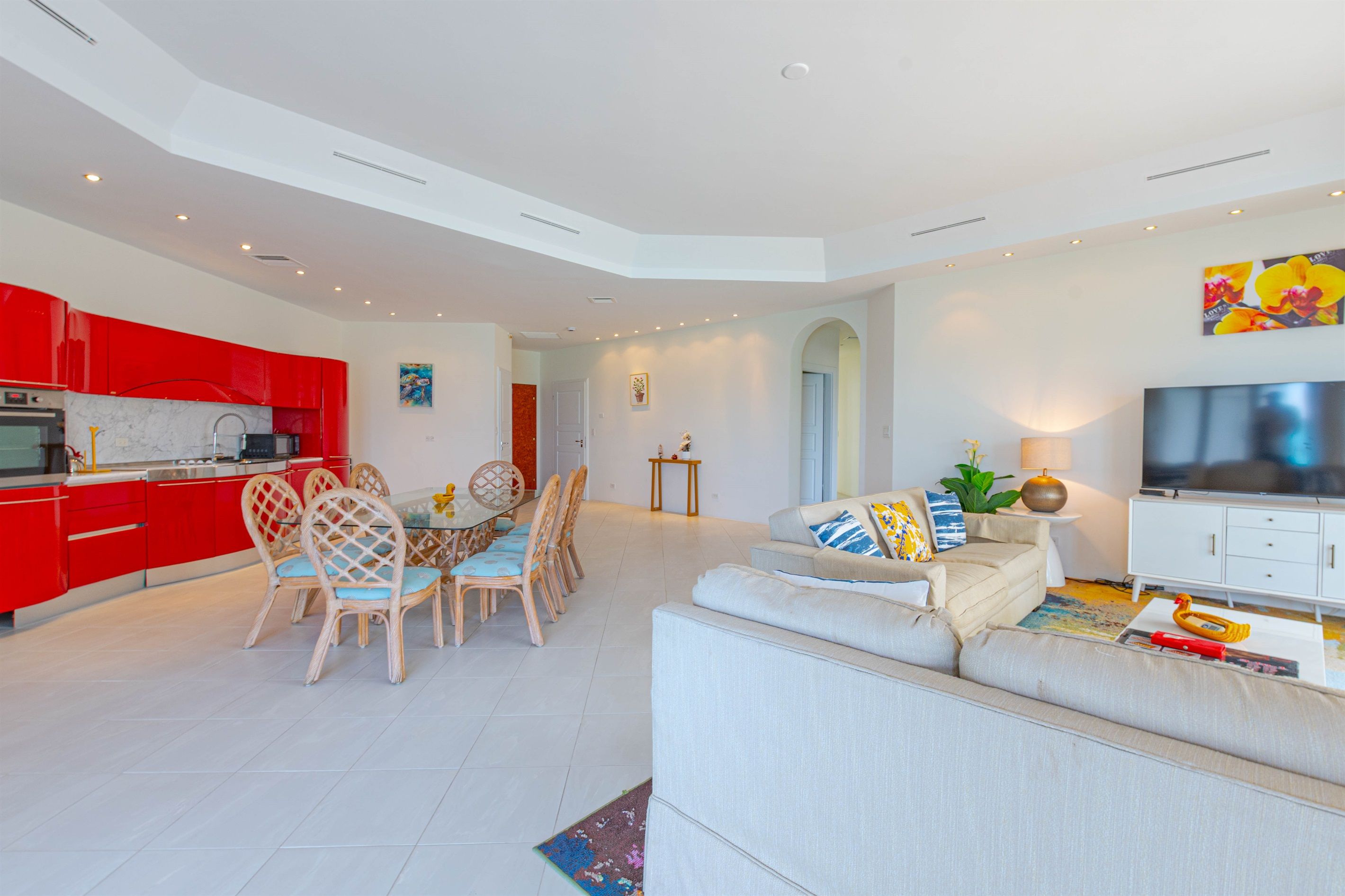 Un salon moderne comprenant un canapé, un téléviseur et un coin repas avec des chaises et une table.