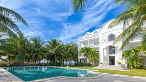 Ein modernes Hotel mit Schwimmbad, Palmen und blauem Himmel.