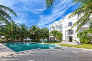 Ein modernes Hotel mit Schwimmbad, Palmen und blauem Himmel.