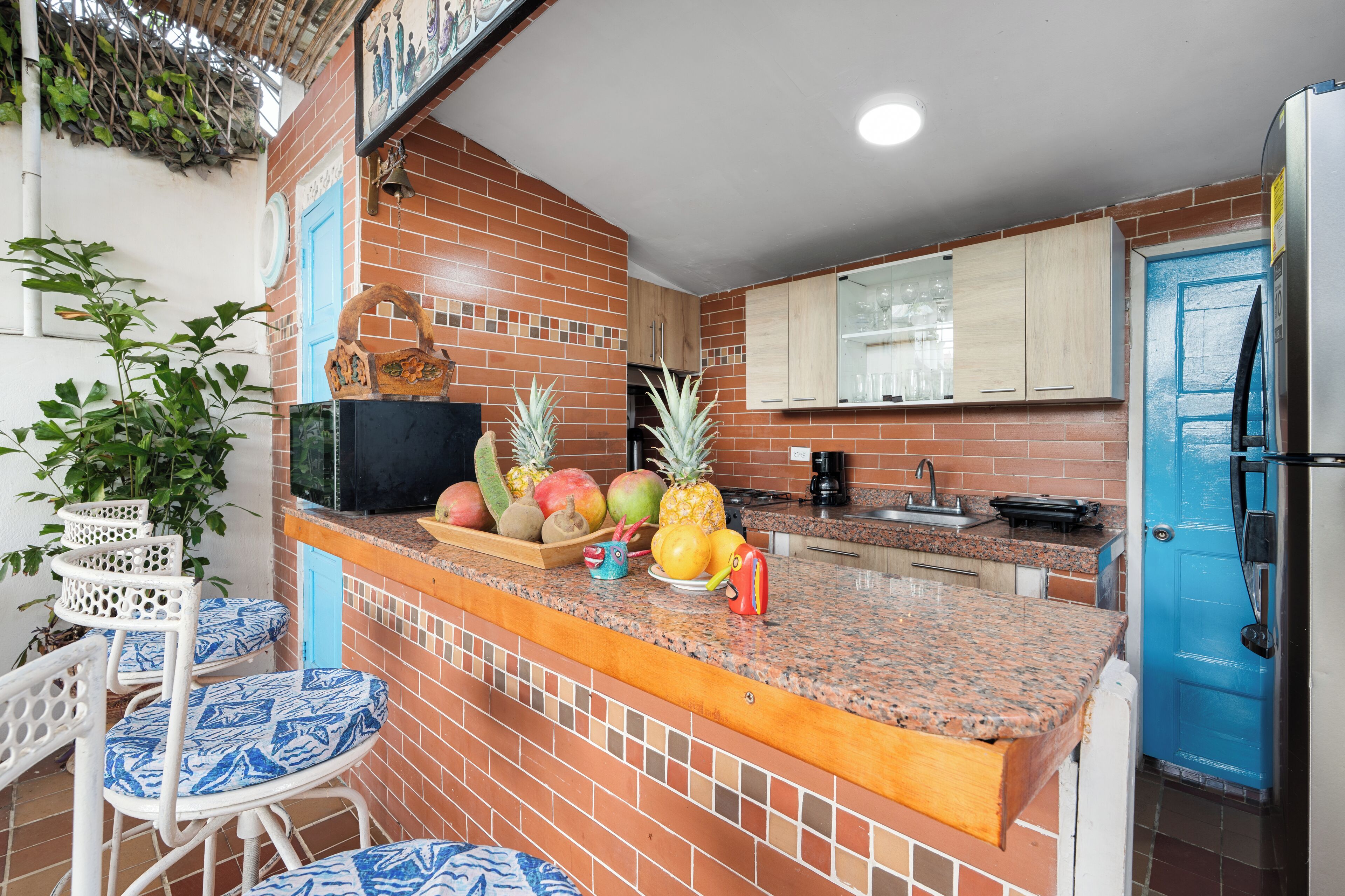 A kitchen with a brick backsplash, a blue door, and a fruit bowl on the counter.