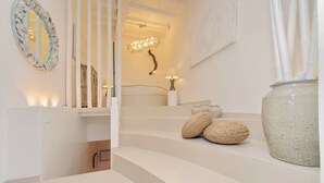 Eine Treppe mit weißer Geländer, ein wandmontierter Spiegel, eine Zierleuchte und eine große Vase.