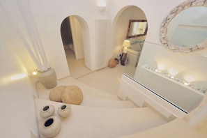 Ein modernes Interieur mit Treppe, Spiegel und einer Sitzecke mit Kissen.