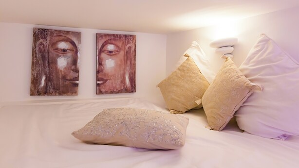 Ein Schlafzimmer mit einem Bett, zwei Wandbildern und dekorativen Kissen.