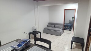 A small, clean room with a grey sofa, a small table, and a chair. - Wonderful 1-bedroom apartment with AC in welcoming Noord (Noord)
