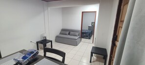 Ein kleines, sauberes Zimmer mit einem grauen Sofa, einem kleinen Tisch und einem Stuhl.