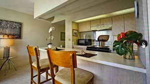 Una cocina moderna con armarios de madera, un microondas y una zona de comedor con dos sillas.