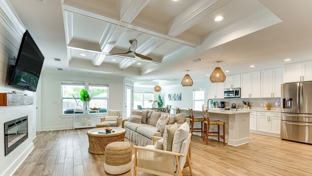 A spacious living room with a fireplace, a large sofa, and a dining area with a high table. - Walk to the beach at Jo Jo's Beach Getaway! (Panama City Beach)