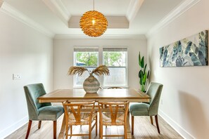 A dining area with a wooden table, four chairs, a woven pendant light, and a vase with dried plants. - Walk to the beach at Jo Jo's Beach Getaway! (Panama City Beach)
