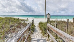 A wooden boardwalk leading to a beach with a signpost. - Walk to the beach at Jo Jo's Beach Getaway! (Panama City Beach)