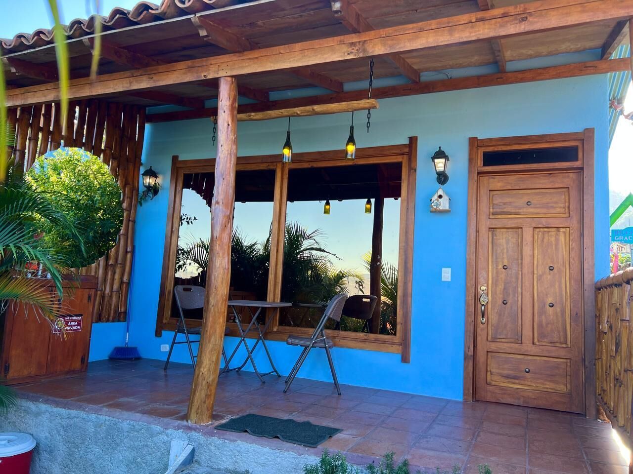 A blue building with a wooden door, windows, and a patio area with chairs and a table.