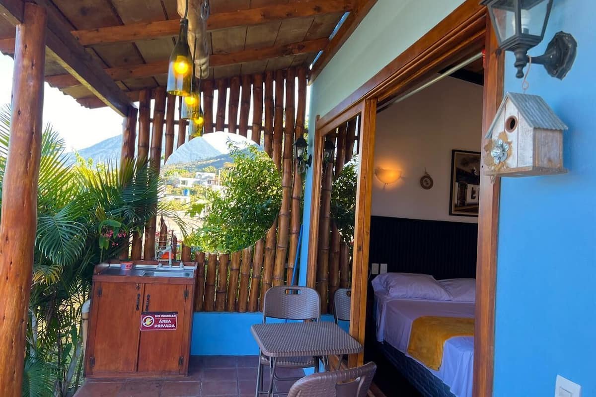 Una habitación con una cama, una mesa, sillas, un armario de madera y una cerca de bambú.