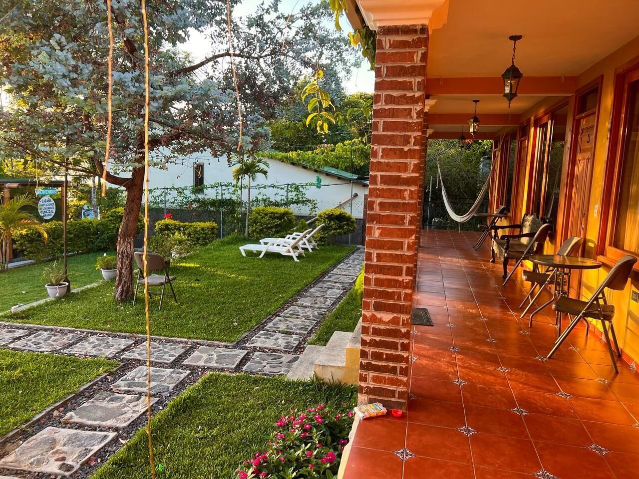 A patio area with a brick column, outdoor seating, and a hammock.