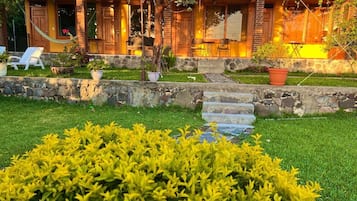 A cozy building with a stone facade, a grassy front yard, and a hammock.