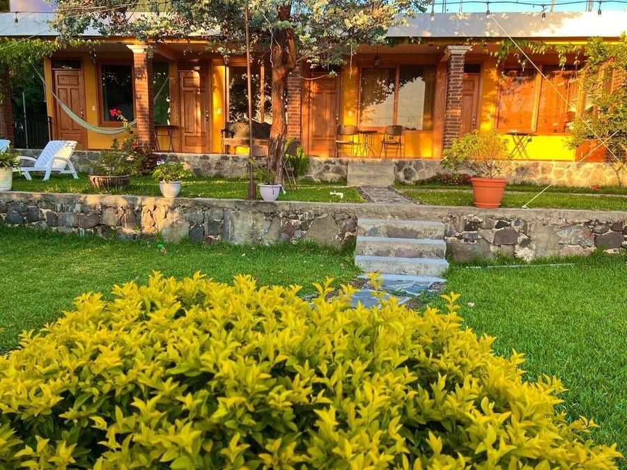 A cozy building with a stone facade, a grassy front yard, and a hammock.