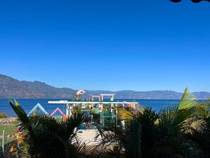 Un petit kiosque situé au bord de la plage, offrant une vue dégagée sur la mer et les montagnes en arrière-plan.