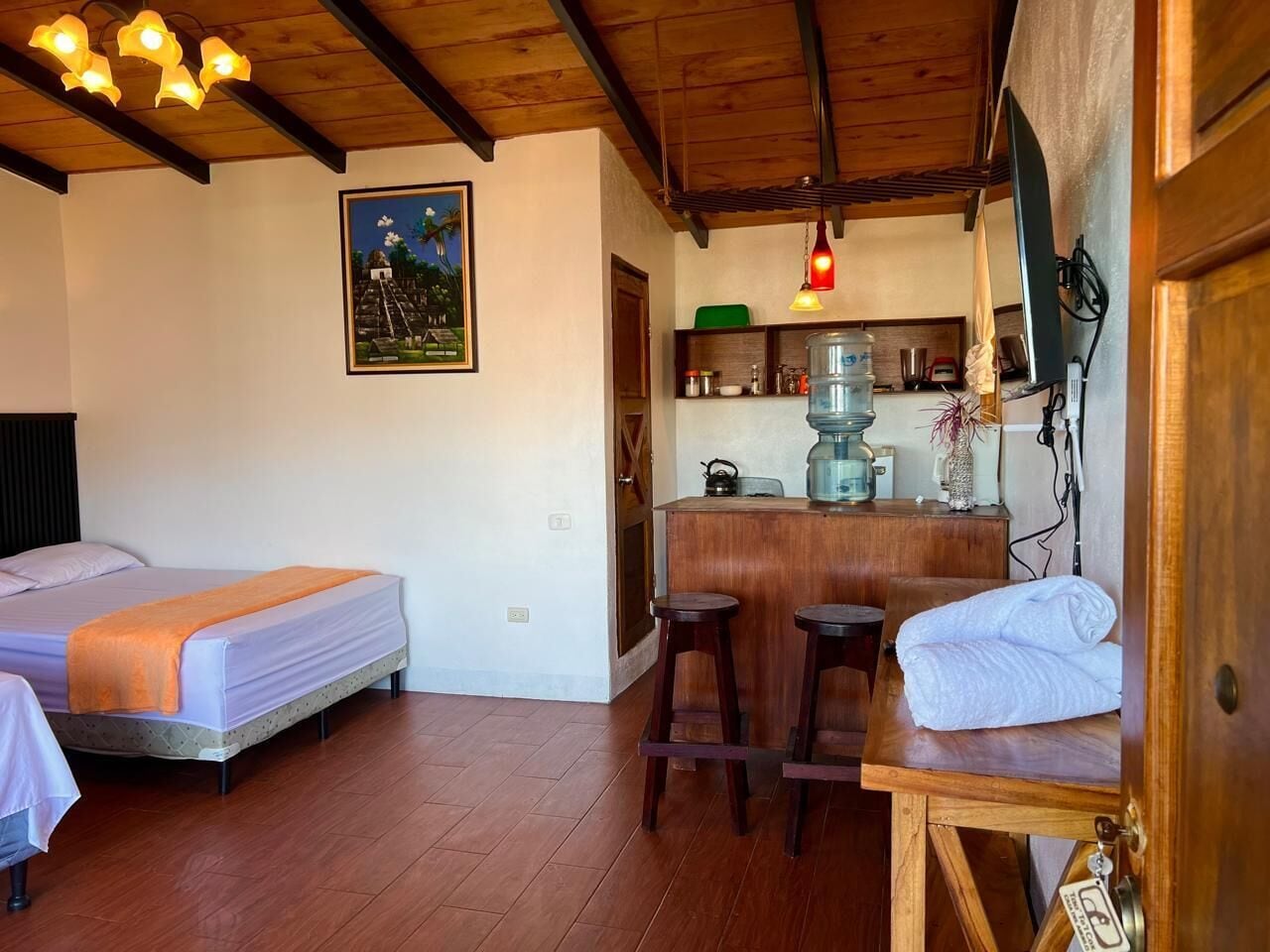 A room with two beds, a kitchen area, and a bar.