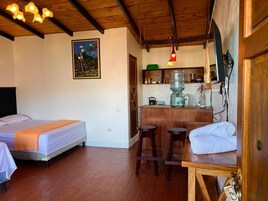 Una habitación con dos camas, una zona de cocina y una barra.