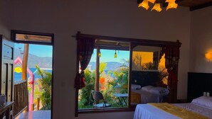 A bedroom with a bed, a chair, and a view of the sea. - Casa del Abuelo (San Pedro La Laguna)