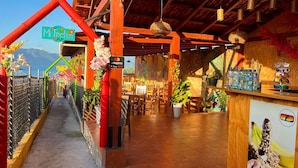 A restaurant with a wooden interior, a sign reading "Mi Pastor", and a view of the mountains. - Casa del Abuelo (San Pedro La Laguna)