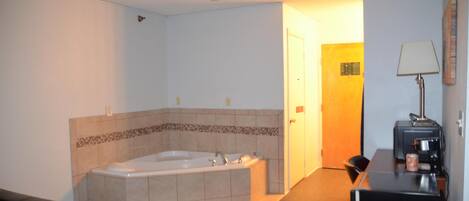 A bathroom with a large bathtub, a toilet, a sink, and a mirror.