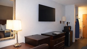 Hotellihuone, jossa on sänky, työpöytä, lipasto, televisio ja lamppu.