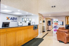 A reception desk with a logo, a counter, and a seating area with a fireplace.