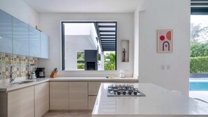 A modern kitchen with a central island, a large window, and a view of the outdoors. - Modern Mediterranean style house in Melgar condominium (Carmen de Apicala)