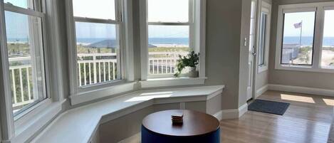 Una habitación con un banco curvo, ventanas amplias y vista al océano.