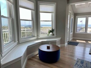 A room with a curved bench, large windows, and a view of the ocean. - Premier Oceanfront Beach Pad 9BR (Atlantic City)