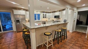 Una cocina moderna con una isla central, taburetes de bar y un refrigerador.