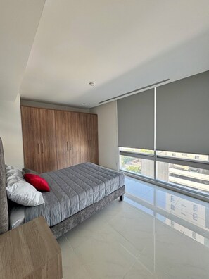 Une chambre à coucher moderne, dotée d’un lit, d’une armoire en bois et d’une grande fenêtre donnant sur la ville.
