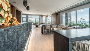 Un interior moderno con barra, asientos y amplios ventanales con vistas a la ciudad.