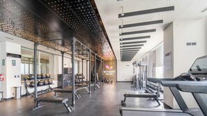 Un gimnasio con cintas de correr, máquinas de pesas y una pared llena de mancuernas.
