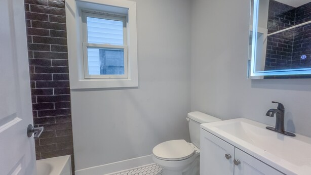 Ein kleines Badezimmer mit Toilette, Waschbecken und Fenster.