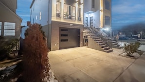 Ein modernes, mehrgeschossiges Gebäude mit einer zentralen Treppe, großen Fenstern und einer Garage.