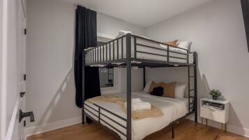 A bunk bed room with a window, a bedside table, and a small plant.